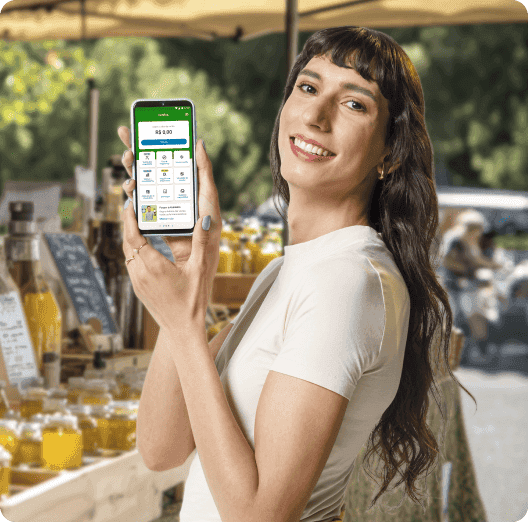 Uma feirante em sua barraca, segurando o celular com o pagamento do Tap On efetuado