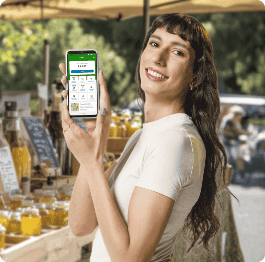 Uma feirante em sua barraca, segurando o celular com o pagamento do Tap On efetuado